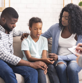 young girl with parents talking to teenager